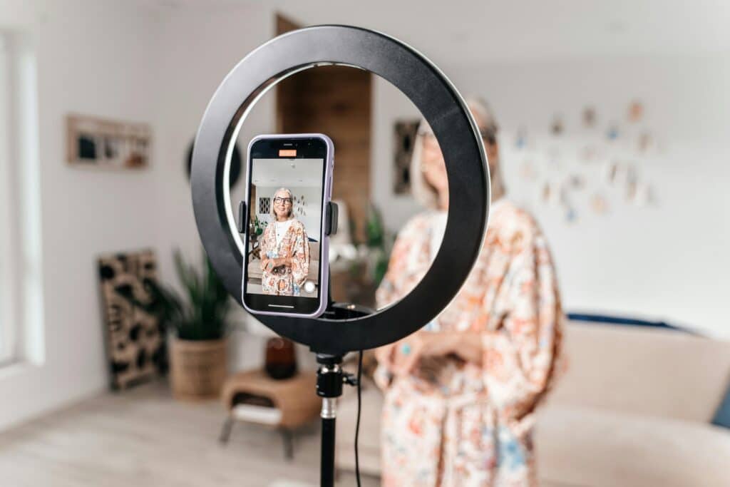 A woman using a ring light to improve video quality when recording video for social media content.
